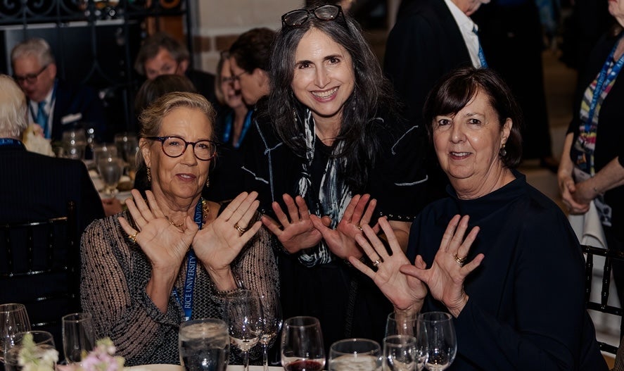 Rice alumni holding up the owl hands gesture at their reunion celebration